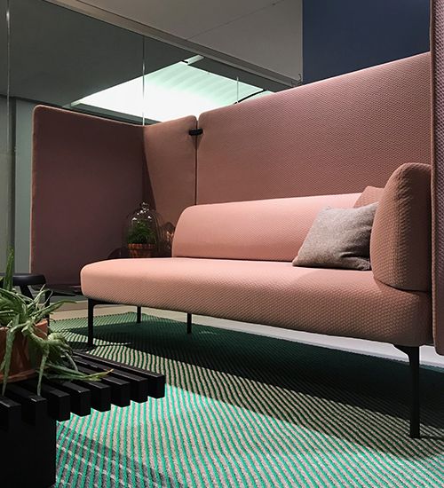 Pale pink sofa with acoustic walls on top of a teal and grey striped rug. Haworth