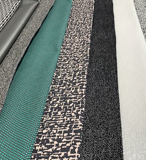 Grey geometric textiles with a pop of teal green laid in a row. Luna Textiles