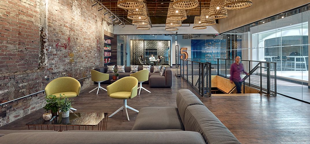 Open workspace with raw brick walls, wood-textured LVT, and plenty of soft textiles to contrast