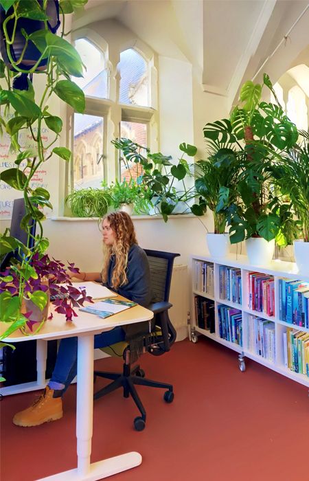 girl sitting at desk in office with plants