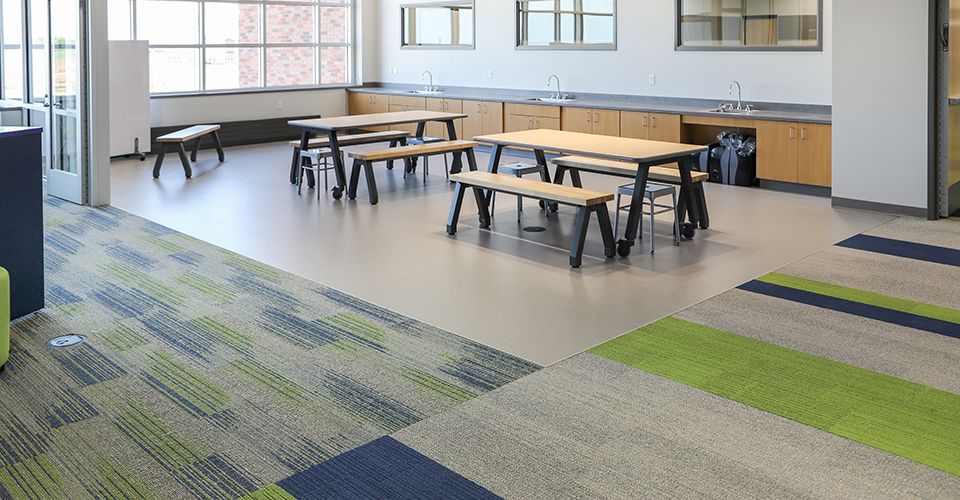 Empty school room with tables, benches, and sink