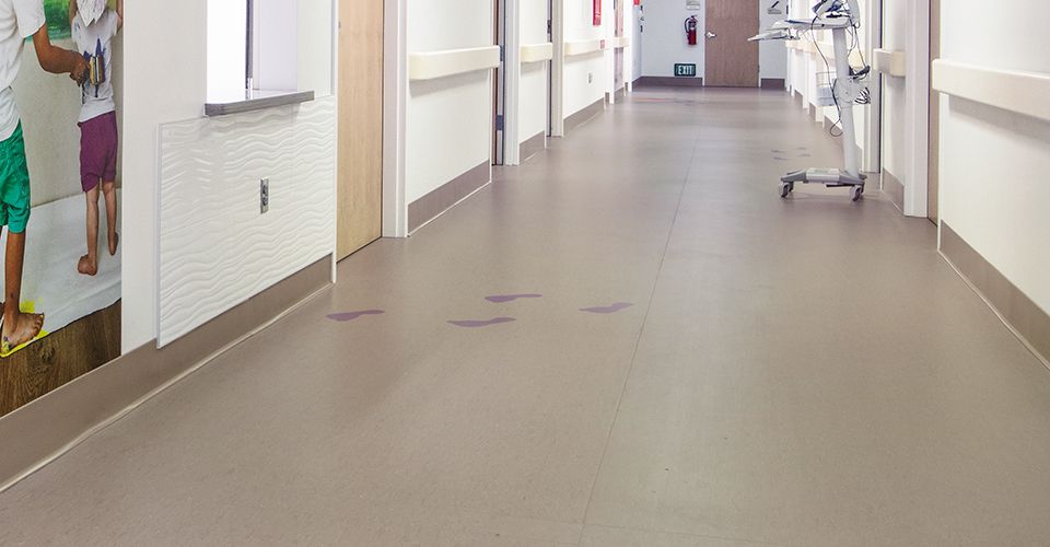 Hospital hallway with purple footprints on grey nora rubber flooring